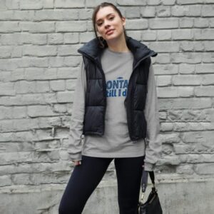 Woman wearing a stylish Montauk sweatshirt, standing near the beach on a breezy day.