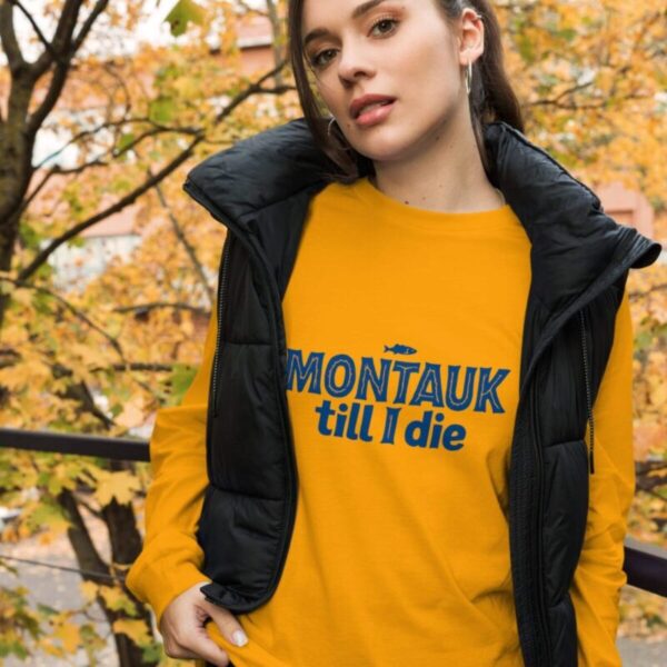 Woman wearing a stylish Montauk sweatshirt, standing near the beach on a breezy day.