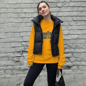 Woman wearing a stylish Montauk sweatshirt, standing near the beach on a breezy day.