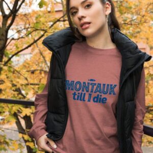 Woman wearing a stylish Montauk sweatshirt, standing near the beach on a breezy day.