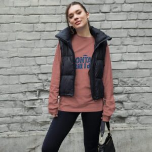 Woman wearing a stylish Montauk sweatshirt, standing near the beach on a breezy day.