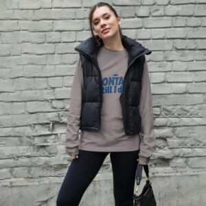 Woman wearing a stylish Montauk sweatshirt, standing near the beach on a breezy day.