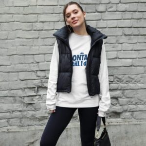 Woman wearing a stylish Montauk sweatshirt, standing near the beach on a breezy day.